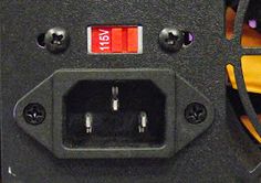 an electronic device with multiple wires and plugs on the back side, in close up view