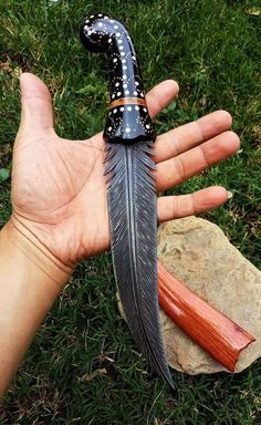 a hand holding a black and white feather knife