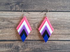 "Make a statement with these colourful chevron earrings! Designed and made by an independent artist in Ontario, Canada Lightweight and comfy for all day wear, each earring weighs less than 4 grams Hanging on stainless steel earring hooks Drop Length = 3\" (75mm) Chevron Size = 2.2\"x1.3\"x0.3\" (55mmx33mmx7mm)  3D Printed in the colours of the Genderfluid pride flag, using strong, lightweight and vibrant PLA filament" Genderfluid Jewelry, Genderfluid Pride, Chevron Earrings, Earrings Colorful, Pride Flag, Earring Hooks, Light Weight Earrings, Stainless Steel Earrings, Pride Flags