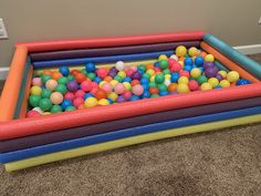 an inflatable ball pit filled with lots of colorful balls on the floor next to a wall