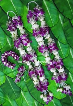 purple and white flowers are arranged on the green leafy surface, with pearls in the center