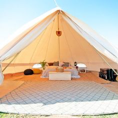 a large tent set up in the middle of a field with chairs and couches