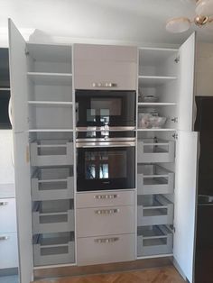 an oven built into the side of a wall in a kitchen with white cabinets and drawers