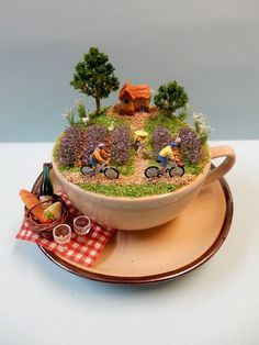 a bowl filled with miniature people riding bikes on top of a table next to a plate