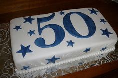 a white cake with blue stars and the number 50 on it is sitting on a table