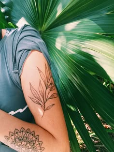 a woman with a tattoo on her arm is sitting next to a leafy plant