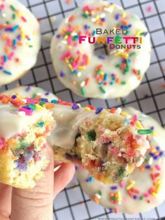 a hand holding a half eaten doughnut with white frosting and sprinkles