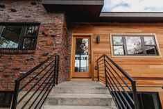 stairs lead up to the front door of a brick building with black railings and windows