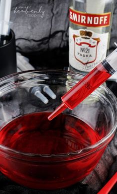 a glass bowl filled with red liquid next to bottles