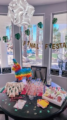 the table is full of candy and confetti for a fiesta themed party in front of large windows with palm trees