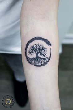 a small tree tattoo on the left inner forearm and arm, with a circle around it