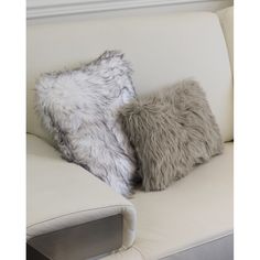 two pillows sitting on top of a white couch