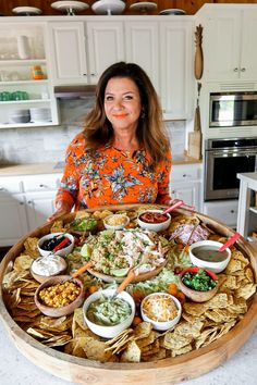 a woman standing in front of a platter full of food