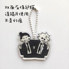 a key chain with an image of two men in suits and pearls attached to it