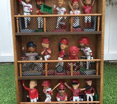 a wooden shelf filled with baseball figurines on top of grass