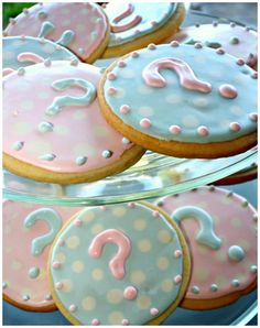 decorated cookies with pink and blue frosting are displayed in a glass dish on a table