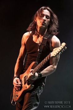 a man with long hair playing an electric guitar