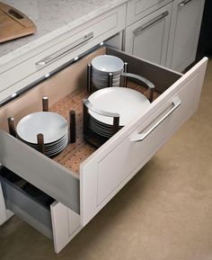 an open drawer in the middle of a kitchen with plates and bowls on top of it