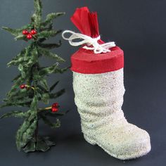 a small christmas tree next to a white and red sock ornament on a black background