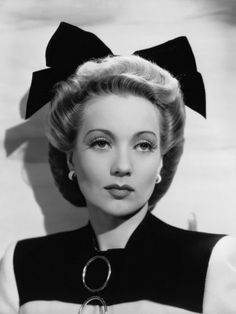 an old black and white photo of a woman wearing a hat with large bows on her head