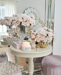 a white table topped with lots of flowers next to a mirror and two stools