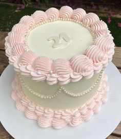 a white and pink cake with pearls on top