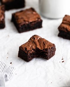 chocolate brownies with frosting cut in half on top of white paper next to a cup of coffee