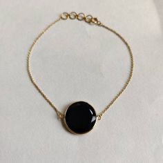 "ITEM DESCRIPTION: >> The bracelet is made from Solid 14K Yellow Gold. Gemstone used is absolutely natural and ethically sourced.  >> Natural Black Onyx in flat cut round shape with bezel setting is studded on it with utmost precision.  >> This is a minimalist design and is absolutely hassle-free and everyday jewelry.  ✓ Gem: Black Onyx ✓ Gem size: 15x15mm ✓ Gem weight: 6.21 carats ✓ Bracelet Length: 7\" Inches + 0.5\" Inch Adjustable ✓ Gold purity: 14K (58.33% approx.) ✓ Gold weight: 1.05 grams  ✓ Gross weight: 2.29 grams The Gold purity is guaranteed and it comes with authentic 14K gold hallmark. Since these Bracelets are handmade, they are Nickel/Lead FREE.  CUSTOMISATION: --> The same design can be made in varying lengths of your choice. --> The same gemstone can be replaced by the one Polished Black Bracelets, Yellow Gold Onyx Jewelry, Elegant Black Chain Bracelet As Gift, Classic Adjustable Black Chain Bracelet, Black Round Jewelry With Adjustable Chain, Black Onyx Round Bracelets, Black Jewelry With Adjustable Round Chain, Gold Onyx Jewelry With Black Enamel, Elegant Black Bracelet With Adjustable Chain