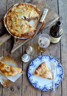 a table topped with pies and drinks on top of a wooden table next to a bottle