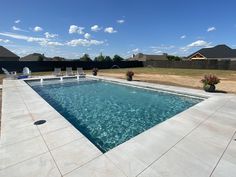 an empty swimming pool in a backyard with lawn chairs and potted plants on the side