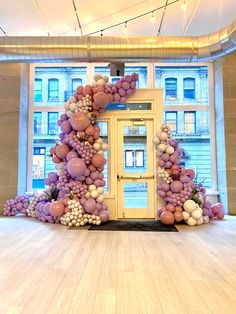 an entrance to a building decorated with purple and white balloons in front of a large window