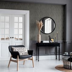 a living room filled with furniture and a round mirror on the wall above a table