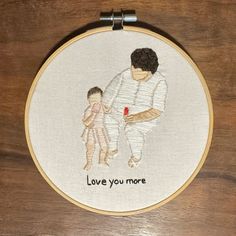 a cross stitch picture with the words love you more and a baby holding a doll