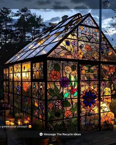 a house made out of stained glass with flowers on the side and lights in the windows