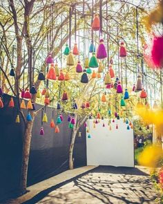 an outdoor ceremony with colorful tassels hanging from the trees