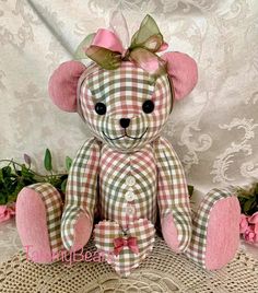 a pink teddy bear sitting on top of a table next to some flowers and greenery