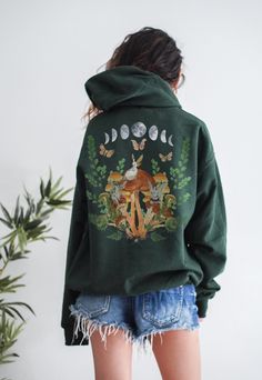 This is a Unisex-Style Fairycore Hoodie. It is a super cool pullover hoodie that is blank on the front with a trendy back print featuring a collage of vintage illustrations salvaged from an old book and watercolor elements. Peep the three small vintage French fairies sitting atop the mushrooms! The soft, warm material is made from a blend of cotton and polyester. It has a front kangaroo-style pocket and no side seams. It is a tried and true hoodie, sure to become your favorite! SIZE UP 1-2 SIZES Jillian Anderson, Indie Sweatshirt, Cottagecore Sweater, Indie Clothing, Sweatshirt Aesthetic, Watercolor Elements, Mushroom Fairy, Aesthetic Hoodie, Vintage Illustrations