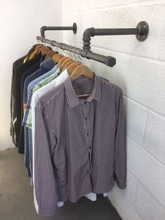 a rack with shirts hanging on it next to a wall