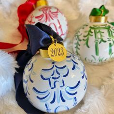 three christmas ornaments with ribbons and tags on them