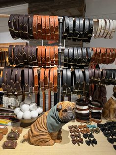 a dog statue sitting on top of a wooden table next to leather belts and other items