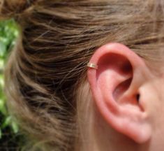 a close up of a person's ear with a tiny gold ring on it