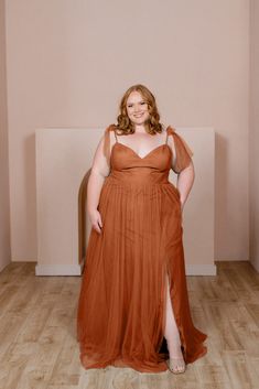 a woman in an orange dress poses for the camera with her hands on her hips