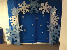 a blue and white backdrop with snowflakes on the front, behind it is a doorway