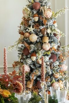 a christmas tree decorated with ornaments and greenery in pink, gold and white colors