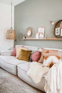 a living room filled with lots of pillows and blankets on top of a white couch