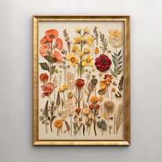 an art piece with flowers on it in a gold frame hanging on the wall next to a white wall