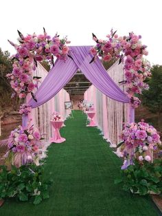 an outdoor wedding setup with purple and pink flowers on the aisle, decorated in lush green grass