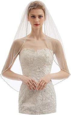 a woman in a wedding dress with a veil over her head and hands on her hips