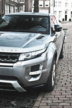 a silver range rover parked on the side of a brick road