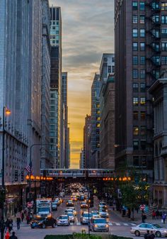 a city street filled with lots of traffic and tall buildings in the background at sunset